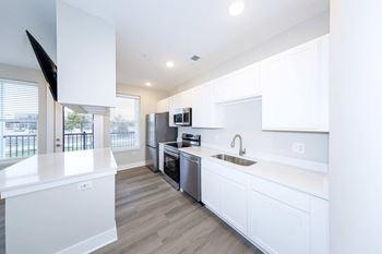 A modern kitchen with white cabinets and stainless steel appliances.